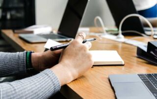 Woman conducting communication audit at desk with computer and notebook