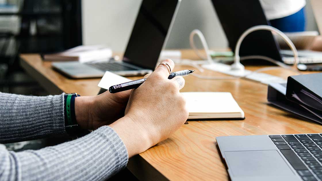 Woman conducting communication audit at desk with computer and notebook